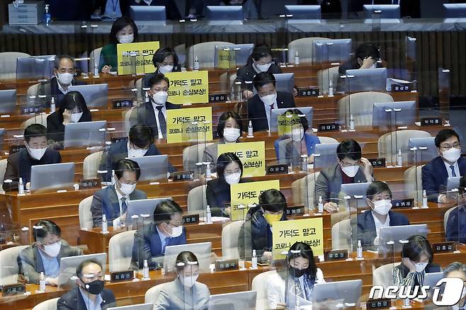정의당 의원들이 26일 서울 여의도 국회에서 열린 본회의에서 가덕도 관련 법안을 비판하는 피켓을 의석에 붙여 놓고 있다. 2021.2.26/뉴스1 © News1 박세연 기자