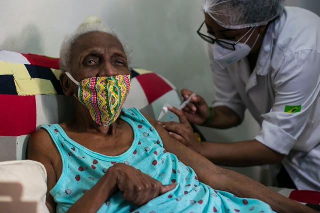 브라질 리우데자네이루에서 의료인이 16일 집밖 외출을 못하는 89세 노인의 가정을 방문해 중국산 시노백 코로나19 백신을 접종하고 있다. 리우데자네이루=AP 뉴시스