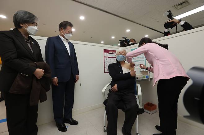 Kim Yoon-tae, a doctor at a children’s hospital, receives a COVID-19 vaccination at a public health center in Mapo, western Seoul, Friday as President Moon Jae-in and Korea Disease Control and Prevention Agency Commissioner Jeong Eun-kyeong watch the process. (Yonhap)