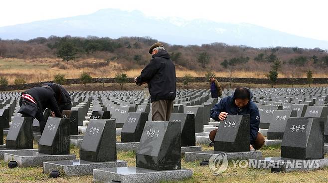 슬픔 닦는 4·3희생자 유족들 (제주=연합뉴스) 4·3희생자 유족들이 제주4·3평화공원 행방불명 희생자 위령비를 찾아 비석을 닦고 있다. [연합뉴스 자료사진]