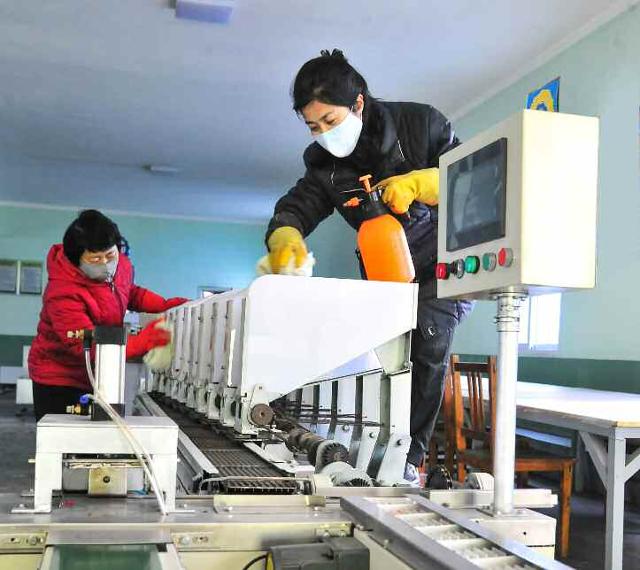 19일 평양학용품공장에서 직원들이 코로나19 방역을 위해 기계를 수건으로 닦고 있다. 평양=노동신문 뉴스1