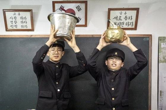 문제원(왼쪽)·안강 학생기자가 양동이와 주전자를 들고 벌을 서고 있다. 작은 소품 하나에서도 옛 감성이 묻어나온다.