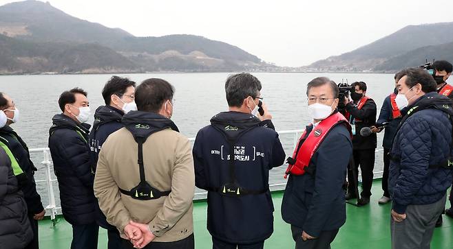 문재인 대통령이 지난 25일 부산에서 열린 '동남권 메가시티 구축 전략 보고'에 참석, 가덕도 공항 예정지를 어업지도선을 타고 시찰하며 이병진 부산시장 권한대행으로부터 관련 보고를 청취하고 있다./연합뉴스