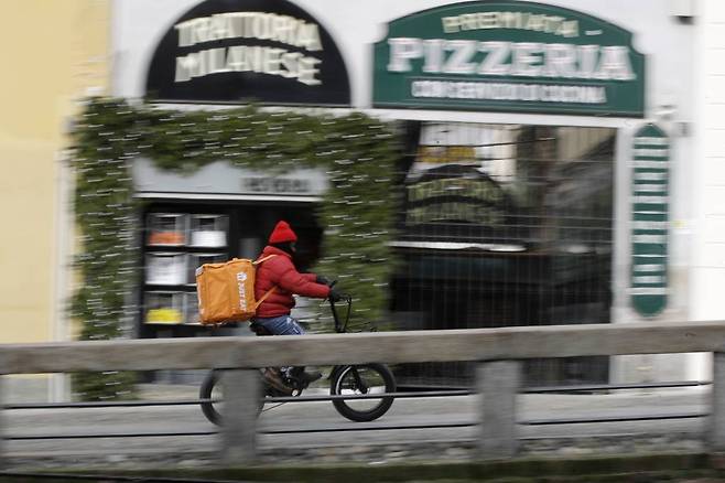 이탈리아 밀라노에서 한 음식 배달원이 오토바이로 음식을 배달하고 있다./사진=[밀라노=AP/뉴시스]