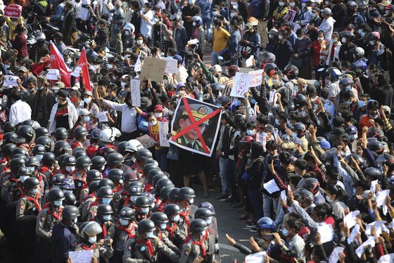 지난달 8일 미얀마의 수도 네피도에서 쿠데타에 항의하는 시민들이 군경과 대치하고 있다. 이들 중 일부가 저항의 의미로 검지·중지·약지를 세우는 '세 손가락 경례'를 하고 있다. 붉은색으로 X표 쳐진 사진의 주인공은 쿠데타의 주역인 민 아웅 흘라잉 장군이다. [AP=연합뉴스]