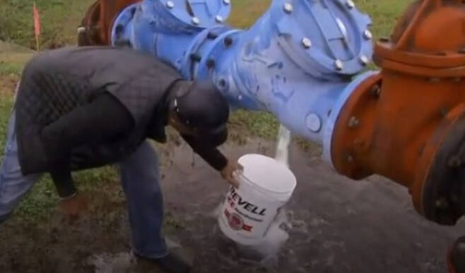 야외 수도 파이프에서 물을 받는 미시시피 주민. BBC 캡처