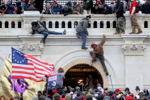 지난 1월 6일(현지 시간) 미국 워싱턴DC 연방의회 의사당에 난입하기 위해 일부 극단주의자들이 벽을 타고 올라가고 있다./로이터연합뉴스