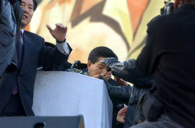 2002년 11월 13일 서울 여의도 한강 변에서 열린 농민대회에서 연설을 하던 노무현 당시 민주당 대선 후보가 농민이 던진 달걀을 맞고 입을 감싸고 있다./연합뉴스