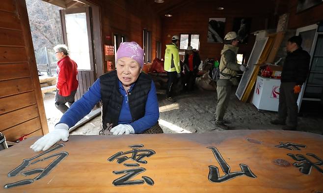 역사 속으로 2019년 12월 2일 백운산장이 폐쇄되면서 산장지기였던 김금자 할머니가 아쉬운 표정으로 현판을 보고 있습니다.