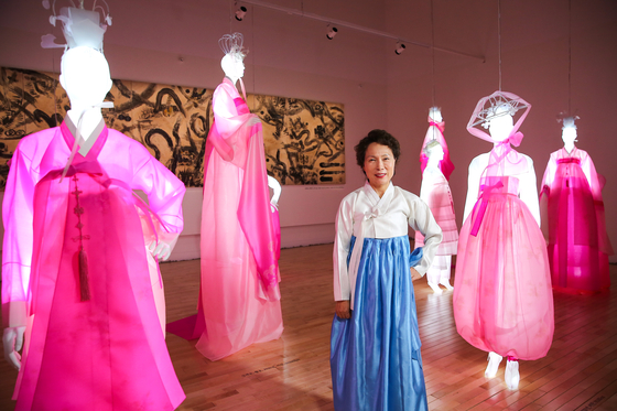 Hanbok designer Kim Hye-soon poses next to mannequins lit up with LED lights and wearing her hanbok at Kim Byung Jong Art Museum in Namwon, North Jeolla. [JANG JUNG-PIL]