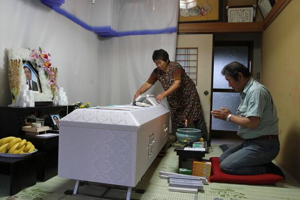 2011년 6월 이타테무라에서 “원전 만이라도 없었다면”이라고 쓴 유언을 남기고 자살한 동료의 관 앞에서 하세가와가 추도하고 있다. 하세가와는 “나쁜 예상이 들어맞고 말았다”며 안타까워 했다고 사진작가 도요다 나오미는 전했다. 두 달 뒤인 8월 마에다지구 구장(한국의 이장)이었던 하세가와는 마을 전 주민이 피난했다고 신고하고, 자신도 인근 다테시 임시 주택으로 거처를 옮겼다. 사진 도요다 나오미 제공