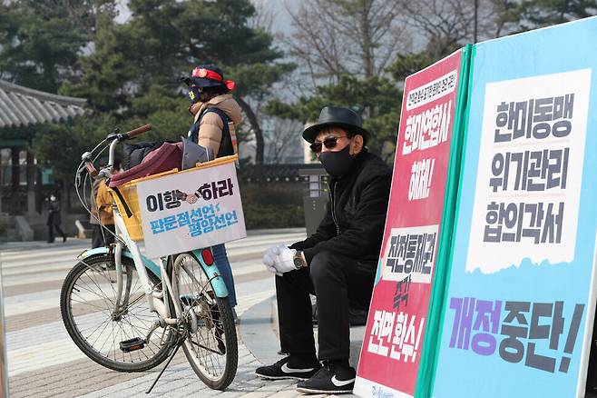 A member of Solidarity for Peace and Reunification of Korea briefly rests beside placards calling for equality in the South Korea-US alliance. The demonstration was held Thursday in front of the Blue House fountain. (Chang Chul-kyu/The Hankyoreh)