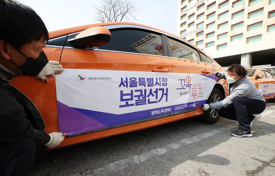 서울시 선거관리위원회가 3일 오후 서울 성북구 대왕기업 택시 차고지에서 서울시장 보궐선거일을 알리고 유권자의 투표 참여를 독려하기 위해 택시에 홍보물을 래핑하고 있다. 뉴시스