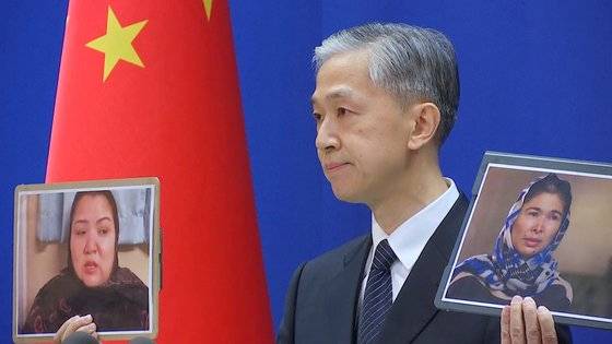 왕원빈 중국 외교부 대변인이 지난달 23일(현지시간) 기자회견에서 위구르수용소 인권 유린 의혹을 폭로한 여성들의 사진을 들어 올리며 관련 보도를 반박하고 있다. [로이터=연합뉴스]