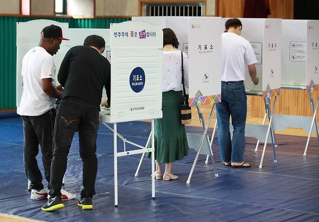 2018년 6·13 전국동시 지방선거 당시 서울 용산구 이태원초등학교 교육문화관에 마련된 투표소에서 나이지리아 출신의 우구오마 오빈나 사무엘(52)씨가 선거사무원의 도움을 받아 기표소에 들어서고 있다. ⓒ연합뉴스