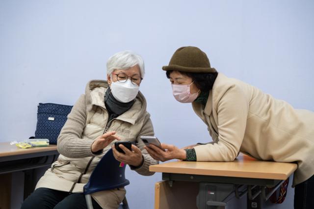 지난달 22일 서울시립은평노인종합복지관에서 노인 수강생들이 디지털 기기 활용 수업 내용을 듣던 도중, 서로의 스마트폰 화면을 공유하며 평소 어려웠던 기능에 대해 상의하고 있다.