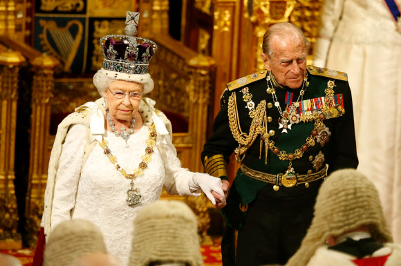 여왕의 퇴장 - 올해 즉위 65년째를 맞은 영국 엘리자베스 2세(왼쪽) 여왕이 18일(현지시간) 런던 의회 의사당에서 국정연설을 마치고 부군 필립공의 손을 잡고 자리를 뜨고 있다.사진=AFP연합뉴스