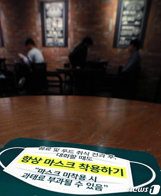 '마스크 착용 의무화 조치' 시행 첫날인 12일 오후 서울 시내의 한 커피전문점 테이블에 마스크 착용 안내 문구가 있다. 이날부터 사회적 거리두기 단계에 상관없이 모든 실내에서 마스크를 착용해야 한다. 미착용자에 대해서는 과태료 10만원, 운영 및 관리소홀 책임이 있는 업주 등 관계자에게는 150만원의 과태료가 부과된다. 2021.4.12/뉴스1 © News1 구윤성 기자