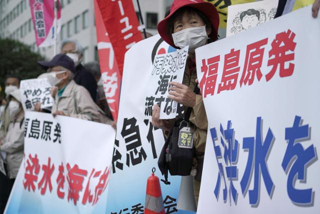 13일 일본 도쿄의 총리관저 밖에서 후쿠시마 원전 오염수 해양 방류에 반대하는 시민들이 '방사능 오염수를 바다에 버리지 말라'라고 쓰인 현수막을 들고 시위하고 있다. 일본 정부는 지역 어민과 주민들의 반대 속에 후쿠시마 원전에서 나온 대량의 방사능 오염수를 2년 후에 태평양으로 방류하기로 했다. 도쿄=AP 뉴시스