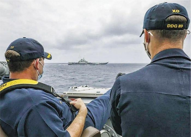 지난 4일 동중국해 해상에서 미군 유도미사일 구축함 USS 머스틴함 함장과 부함장이 중국 인민해방군 항공모함 랴오닝함을 지켜보고 있는 모습. 미 해군이 12일(현지시간) 공개했다. 연합뉴스
