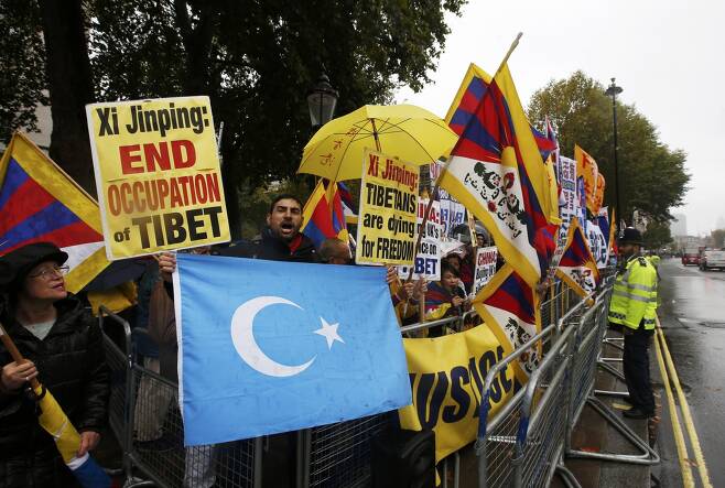 영국 런던 중심가 다우닝가에서 한 남성이 친티베트 지지자들 사이에서 위구르 깃발을 흔들며 시진핑 중국 국가주석 반대 시위를 벌이고 있다. / 사진=로이터