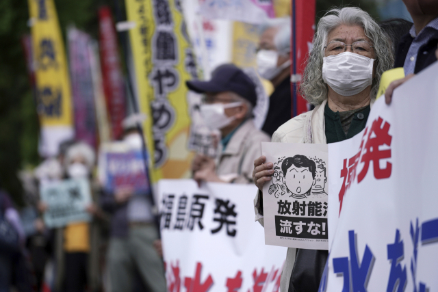 13일 일본 도쿄 총리관저 앞에서 시민들이 플래카드를 들고 정부의 후쿠시마 원전 오염수 해양 방류 결정에 대한 반대 시위를 벌이고 있다. 이날 일본 정부는 지난 2011년 후쿠시마 제1 원전 사고로 발생한 방사성 물질 오염수 125만여t을 바다에 배출하기로 했다./AP연합뉴스