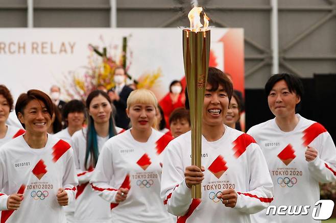 일본 여자 축구 대표 선수들이 25일 (현지시간) 후쿠시마현 나라하에서 도쿄 올림픽 성화 봉송 첫 주자로 뛰고 있다. © AFP=뉴스1 © News1 우동명 기자