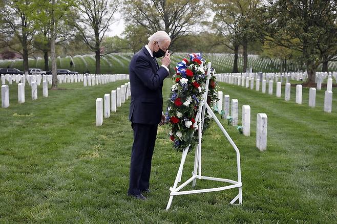 조 바이든 미국 대통령이 14일(현지시각) 버지니아주 알링턴국립묘지 내 2001년 테러와의 전쟁 이후 숨진 미군들이 안장된 ‘60구역’에서 헌화하고 성호를 긋고 있다.  알링턴/EPA 연합뉴스