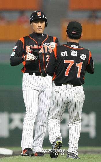 롯데 조성환(왼쪽)이 2009년 6월 2일 안면 사구 부상 복귀전에서 2루타를 때린 뒤 이철성 코치에게 장비를 넘기고 있다. | 경향DB