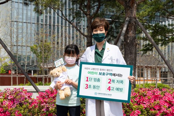 유경하 이화의료원장(오른쪽)이 서울 가곡초등학교 3학년 장연규 어린이와 함께 4월 21일 "어린이 보호구역 교통안전 릴레이 캠페인"에 참여하고 있다. 사진=이화의료원