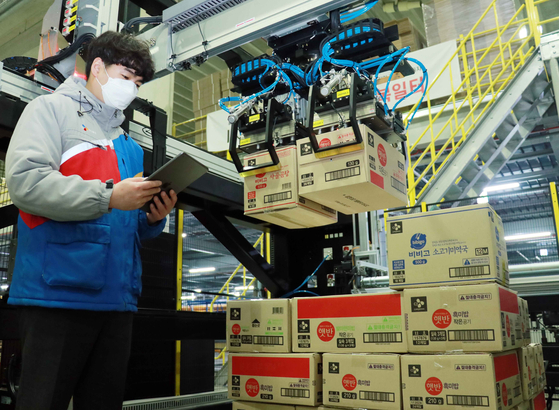 A CJ Logistics employee operates robotic arms to move around boxes at one of the logistics company's warehouses. The company on Thursday announced the commercial use of the artificial intelligence-operated robotic system in its conveyor line. [CJ LOGISTICS]