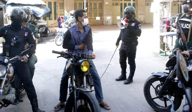 캄보디아 수도 프놈펜에서 오토바이에 탄 시민을 에워싸고 회초리를 들고 있는 경찰 [크메르타임스 사이트 캡처. 재판매 및 DB 금지]