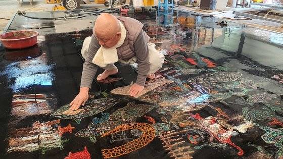 성파 스님이 맨발로 반구대 암각화 작품 위에 올라가 작업을 하고 있다. 우주에 띄워진 그림의 색상이 선명하다.