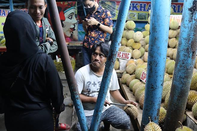 손님에게 두리안 맛을 보여주려는 아구스씨 [자카르타=연합뉴스]