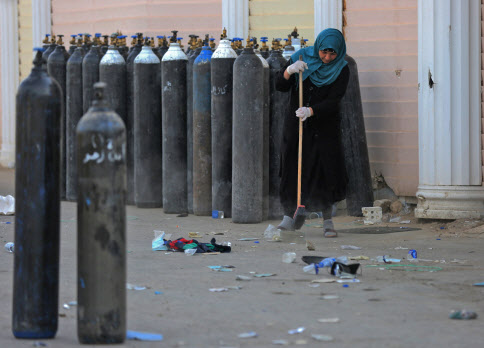 이라크 코로나19 환자 치료 병원 화재 발생 후 청소하는 관계자.[사진=AFP]