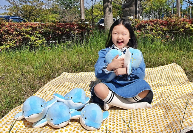 사회적 기업 우시산이 페트병 7개로 업사이클링한 상괭이 인형을 아이가 안고 있다<사진=SK이노베이션>