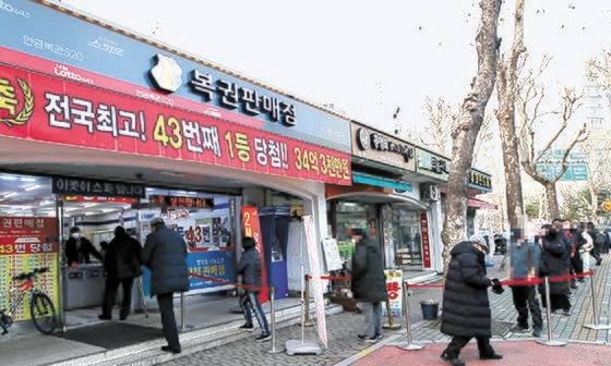 ‘로또 명당’으로 알려진 서울 노원구의 한 복권판매점 앞에 시민들이 로또를 사기 위해 줄을 서 있다. [뉴시스]