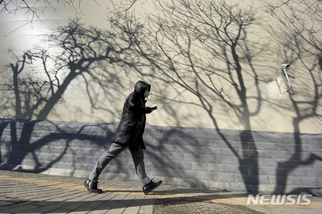 [베이징=AP/뉴시스]3일(현지시간) 화창한 날씨를 보인 중국 베이징에서 한 남성이 나무 그림자가 드리운 거리를 지나고 있다. 2020.03.03.