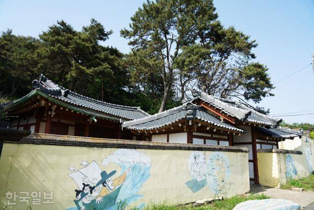 느러지마을 최부 묘소 앞의 사당. 빛바랜 담장 그림이 조금은 장난처럼 보인다.