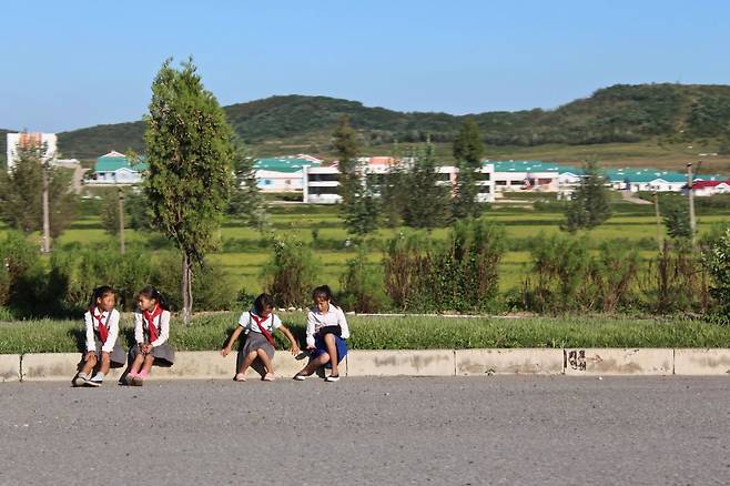 A group of children sit by the roadside on Youth Hero Highway in September 2018. (Lindsey Miller)