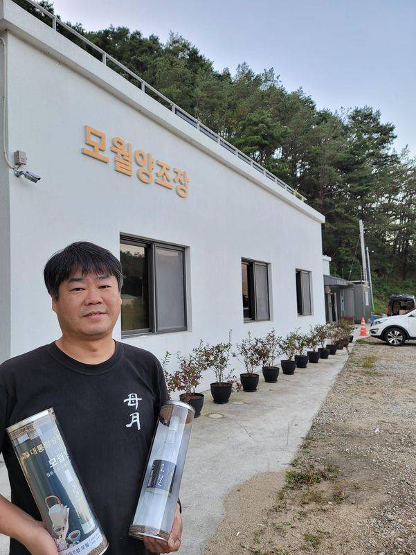 김원호 대표가 모월양조장을 배경으로 대통령상을 받은 모월인 소주를 들고 있다. 양조장 주변에는 조만간 트레킹코스, 한옥체험마을 등이 들어선다. 대하민