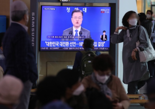 On May 10, citizens at Seoul Station watch President Moon Jae-in’s special address marking four years in office on TV. Yonhap News