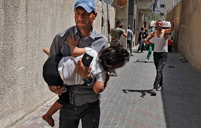 <YONHAP PHOTO-4199> 이스라엘군 공습에 아이 안고 대피하는 팔레스타인 남성       (가자시티 AFP=연합뉴스) 11일(현지시간) 팔레스타인 가자지구의 중심도시 가자시티에서 이스라엘군의 공습으로 한 남성이 아이를 품에 안은 채 대피하고 있다. 이슬람의 3대 성지 알아크사 사원 내에서 벌어진 팔레스타인 시위대와 이스라엘 경찰의 충돌 이후 이스라엘군과 가자지구를 통치하는 무장 정파 하마스의 무력 충돌이 이틀째 이어지고 있다.     leekm@yna.co.kr/2021-05-11 19:53:12/ <저작권자 ⓒ 1980-2021 ㈜연합뉴스. 무단 전재 재배포 금지.>