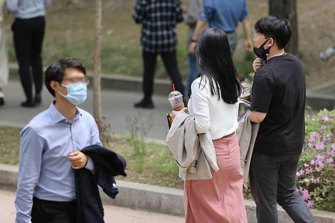 낮 기온이 27도까지 올라가며 여름 날씨를 보인 지난달 22일 낮에 서울 여의도공원에서 시민들이 외투를 벗어 팔에 걸친 채 걸어가고 있다. 연합뉴스