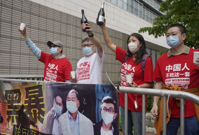 홍콩의 친중 시위대가 지난 4월 16일 반중매체인 빈과일보의 사주 지미 라이를 포함한 범민주진영 인사들의 재판이 열리는 법원 주변에서 이들의 실형 선고를 축하하며 샴페인 병을 치켜들고 있다. AP연합뉴스
