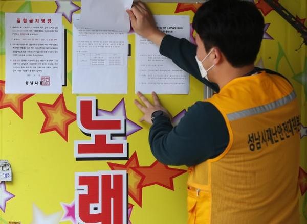 13일 오후 경기도 성남시의 한 노래방에서 성남시 공무원이 집합금지 행정명령서를 붙이고 있다.