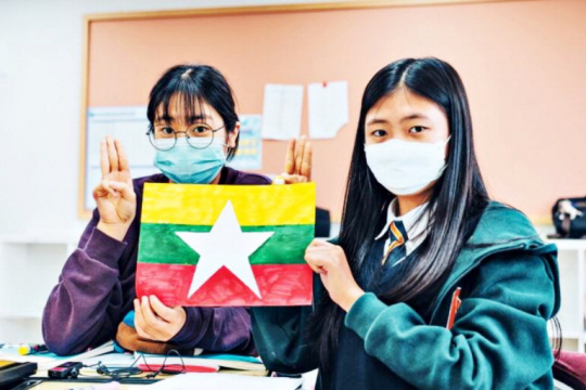 미얀마를 위한 헌정곡 ‘미얀마의 봄’을 발표한 소녀 가수 완이화(오른쪽)가 직접 그린 미얀마 국기를 들어서 보여주고 있다.  중앙예닮학교 제공
