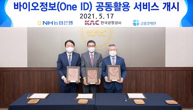 NH NongHyup Bank CEO Kwon Joon-hak (first from left), Kim Hak-soo, president of the Korea Financial Telecommunications and Clearings Institute (center) and Korea Airports Corp. President and CEO Son Chang-wan hold up their hand prints during an event celebrating the launch of a joint bioinformation service at Gimpo International Airport, Monday. (NH NongHyup Bank)