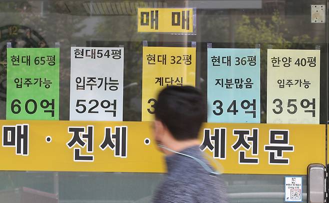 지난달 11일 서울 강남구 압구정동의 부동산중개업소에 붙어 있는 시세표를 길을 가던 시민이 바라보고 있다. 연합뉴스