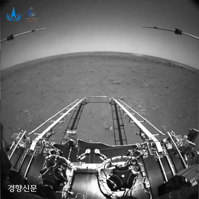 중국 국가항천국(CNSA)이 19일(현지시간) 공개한 화성 지상탐사 로버 ‘주룽’의 첫 촬영 사진. 주룽 전면의 장애물 회피용 카메라로 찍었다. 주변의 넓은 평지와 광각 렌즈로 인해 동그랗게 왜곡된 지평선이 보인다. AP연합뉴스